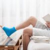 Man with a broken leg in a cast sits at home and reads books.