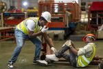 Factory worker having accident while working in manufacturing site while his colleague is asking for first aid emergency team using walkie talkie radio