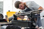 The gunsmith maintaining his rifle in a workshop