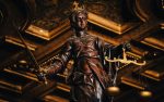 Wooden statue of Lady Justice holding scales and a sword