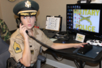 sitting at desk answering phone, checking files, computer