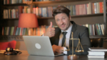 Male lawyer or bail bond person doing thumbs up while working on laptop