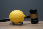 A lemon with wheels and a judge gavel. Lemon law concept.