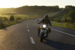 Motorcyclist riding on a road during what appears to be sunrise or sunset