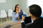 Woman with neck brace and arm sling consulting with an insurance agent about her personal injury claim in a modern office setup