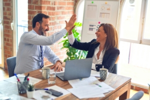 Two colleagues, giving each other a high-five in an office environment