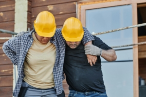 workplace injury in a construction setting, with one worker assisting an injured colleague