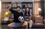 a couple excitedly watching a football (soccer) match at home