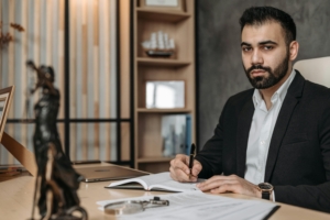 professional in an office setting working at a desk, with a figurine of Lady Justice visible in the foreground