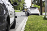 white car with rear-end damage on the side of a road