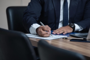 a person in business attire signing documents at a desk