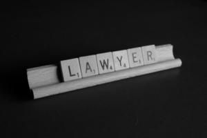 Scrabble tiles arranged on a rack to spell the word "LAWYER"