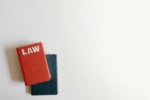 a red hardcover law textbook placed on top of a dark blue book on a white surface