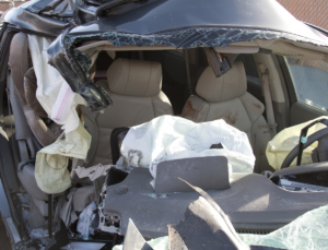 A terribly mangled car with blood on the driver's seat.