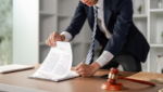 Young Asian lawyer reviewing and signing legal contract documents at office desk, focusing on law practice.