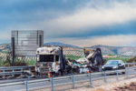 Completely burned-out truck after catching fire on the road, highway with olive fields in the background.