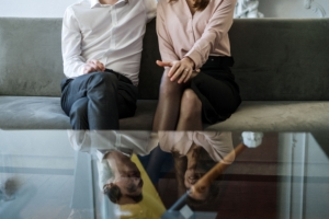Couple sitting on a sofa reflecting on a glass table during a consultation