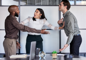 Shot of a young businesswoman trying to stop her two colleagues from fighting in an office