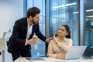 A woman at work rebuffs unwanted attention from a male colleague, conveying discomfort and rejection with body language.