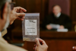Middle Aged Caucasian Man Presenting Evidence Bag Containing Rings in Courtroom