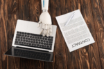 cropped shot of robot working with laptop on wooden surface with business contract