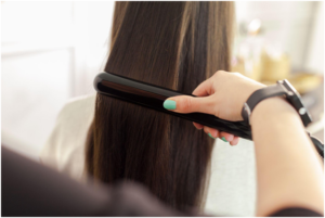 Using a flat iron to style and straighten long dark hair as an example of a product you can get injured using