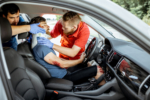 Medics wearing neck corset to an injured man sitting in the car after the road accident, providing emergency medical assistance
