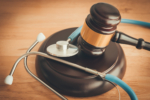 Judge hammer gavel and doctor stethoscope on wooden table background in courtroom.