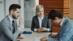 Professional business or legal meeting with three people seated around an office table