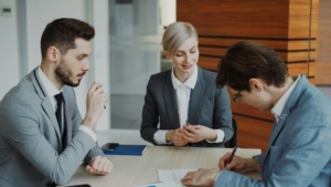 Professional business or legal meeting with three people seated around an office table