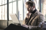 man in a jacket looking at an open laptop