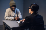 A black guy listens to his rights from a civil lawyer at a table in a visiting room in a state prison