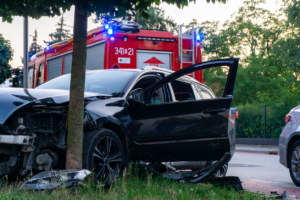 Damaged passenger car after road accident, fire brigade on scene