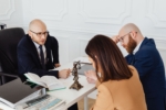 Consultation scene featuring a lawyer or advisor seated behind a desk across from a client or couple