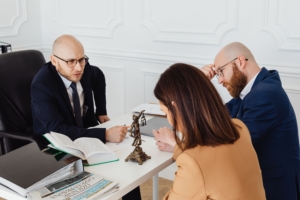 Consultation scene featuring a lawyer or advisor seated behind a desk across from a client or couple
